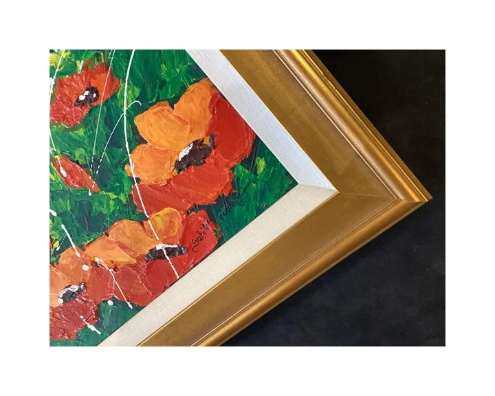 Close-up of a framed painting of red and orange poppies with green foliage.