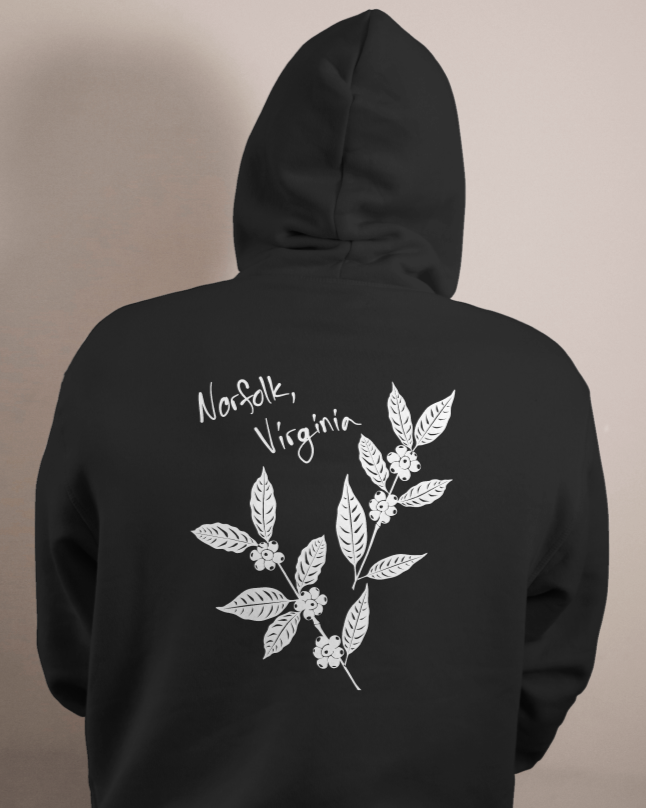 Back of a black hoodie with white illustration of coffee plant leaves and berries, and handwritten text 'Norfolk, Virginia'.