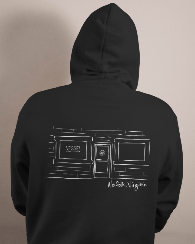 Back of a person wearing a black hoodie with a white line drawing of a building with two windows and a door, labeled 'Vessel Craft Coffee' and 'Noa Folk, Virginia'.