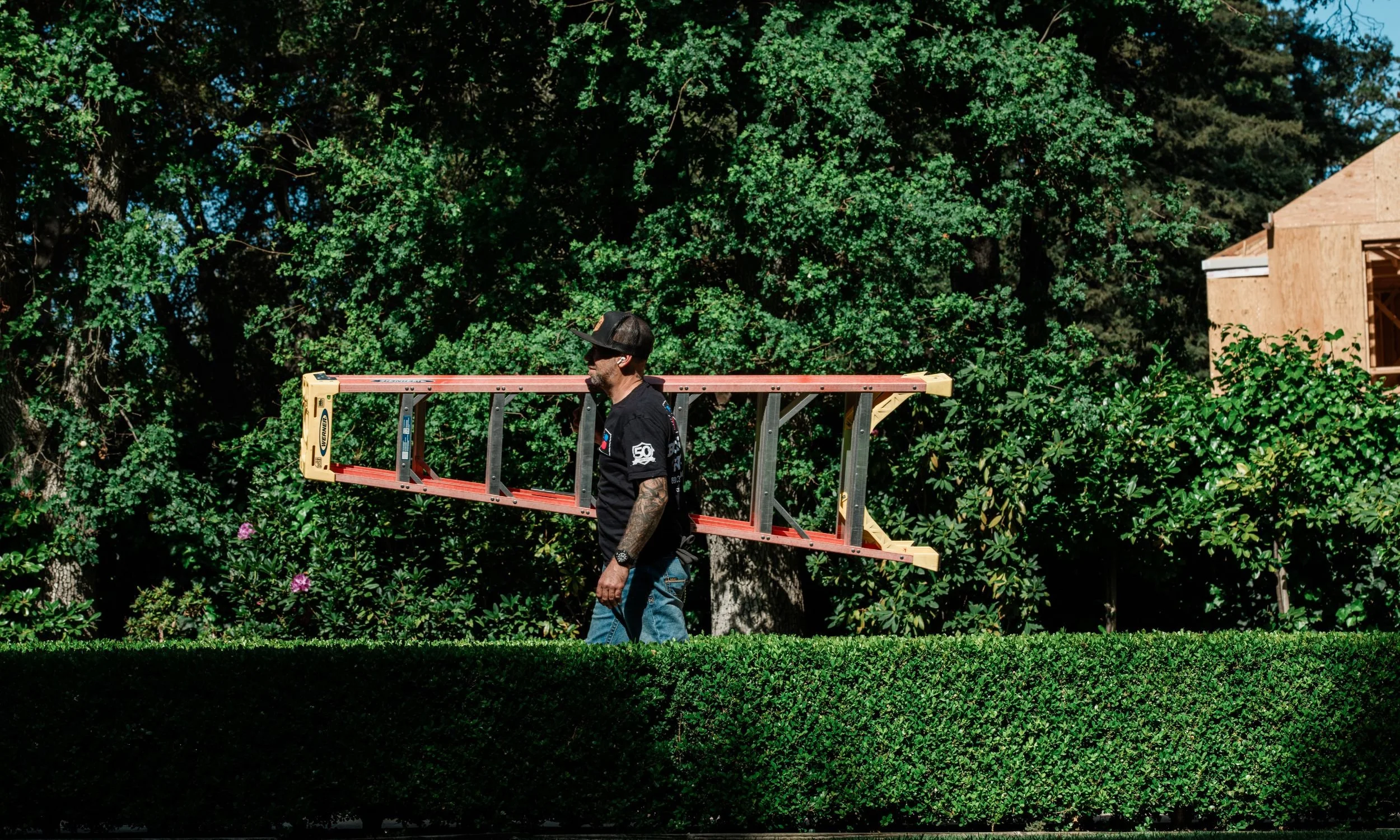 A Bodnar HVAC technician walking toward a high-end residential home with equipment, providing professional heating and air conditioning service.