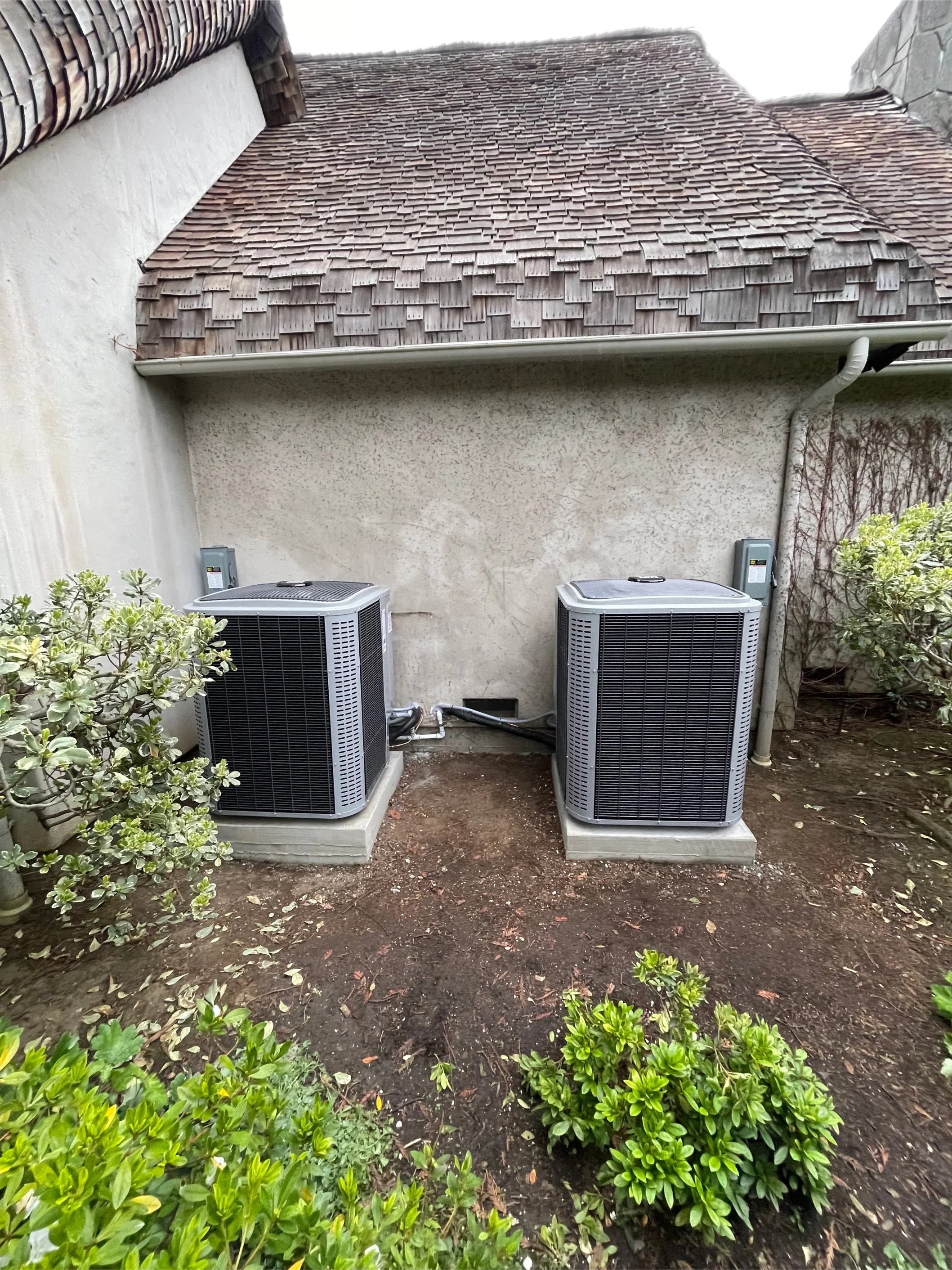 Dual high-efficiency air conditioning condensers installed on level concrete pads with professional electrical disconnects and clean lineset routing for a luxury residence in Atherton, CA