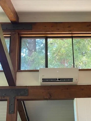 Indoor ductless mini-split wall unit mounted precisely above a structural wood beam in a home with vaulted ceilings, providing quiet heating and cooling in Redwood City, CA.