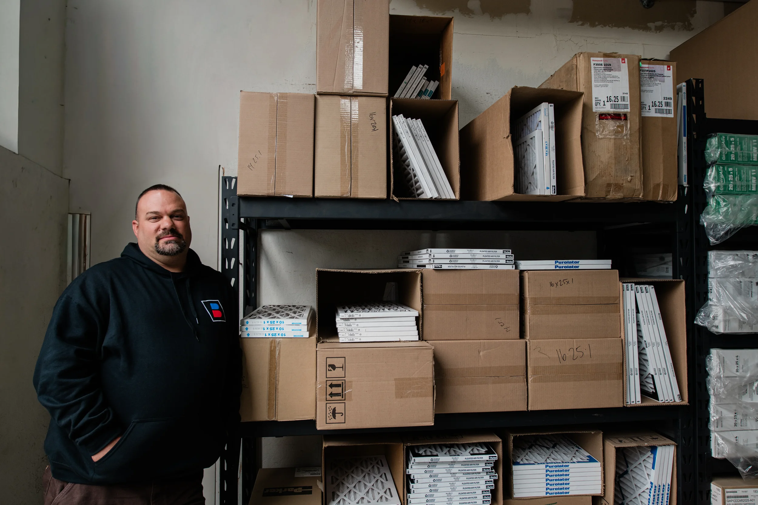 Ted Becker standing next to a fully stocked inventory of air filters and furnace components, reinforcing Bodnar HVAC’s commitment to immediate, honest maintenance without requiring a monthly service plan.