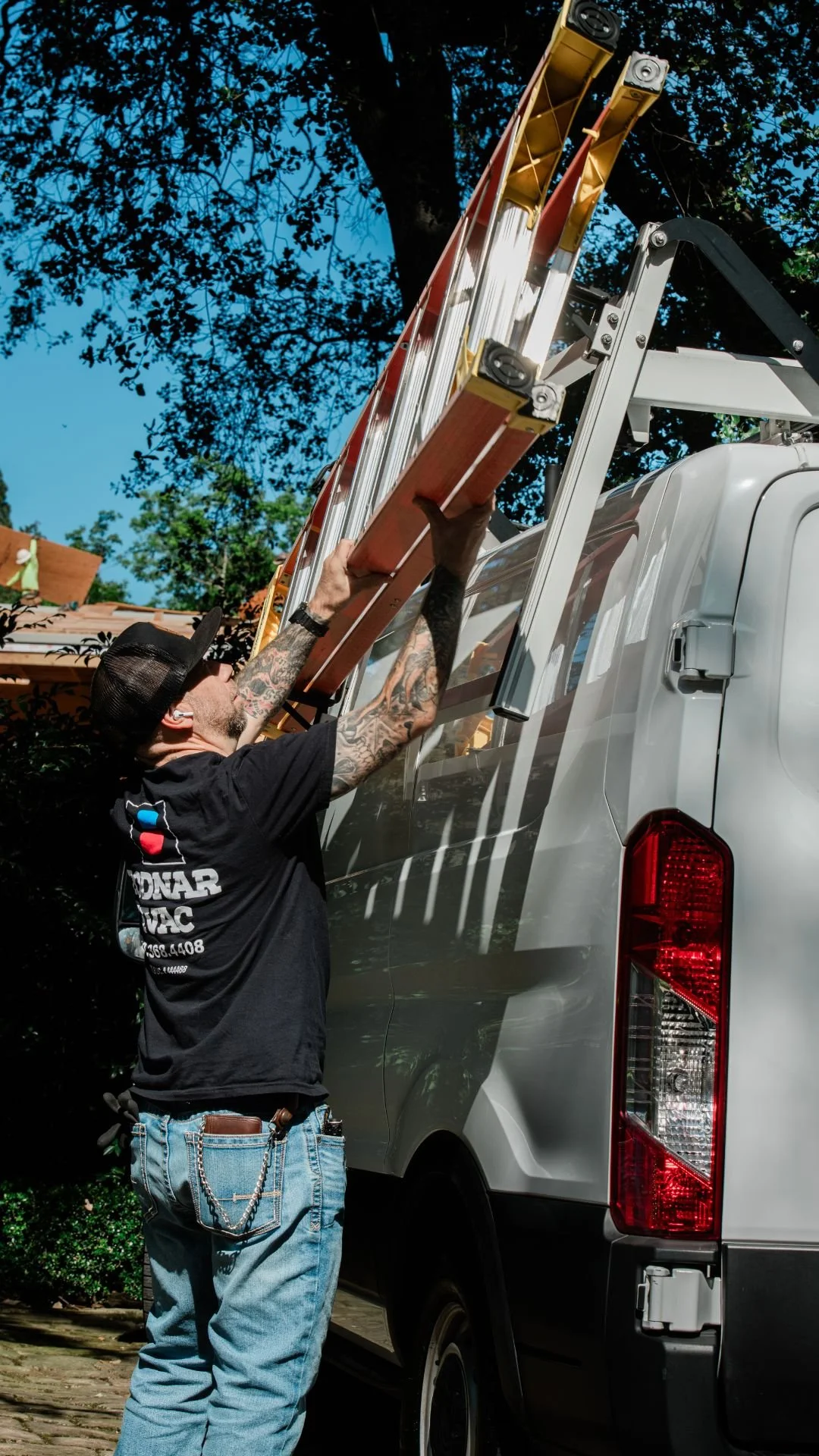 Bodnar HVAC technician unloading a ladder from a branded service van to perform a residential AC repair in Redwood City.