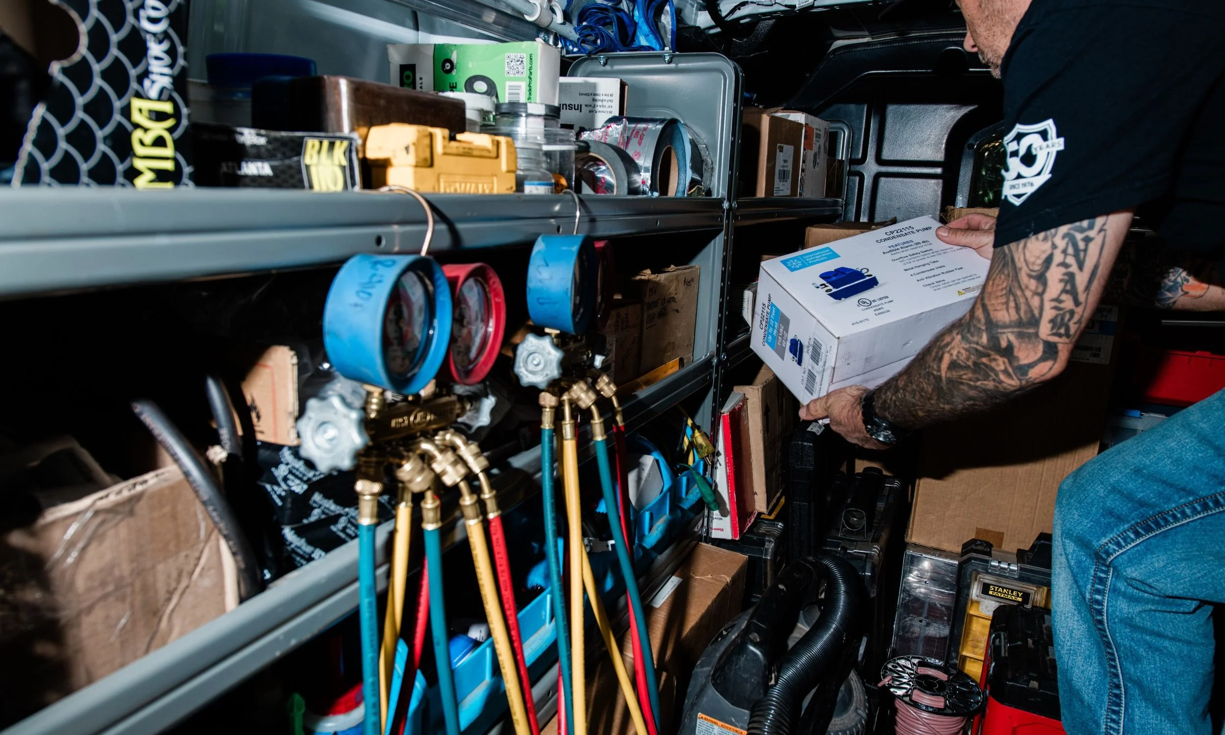 A professional HVAC technician organizing manifold gauges and high-quality replacement parts inside a service van, demonstrating the transparency and preparation that defines Bodnar HVAC’s trusted service.