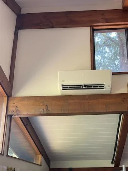 Indoor ductless mini-split wall unit mounted precisely above a structural wood beam in a home with vaulted ceilings, providing quiet heating and cooling in Redwood City, CA.