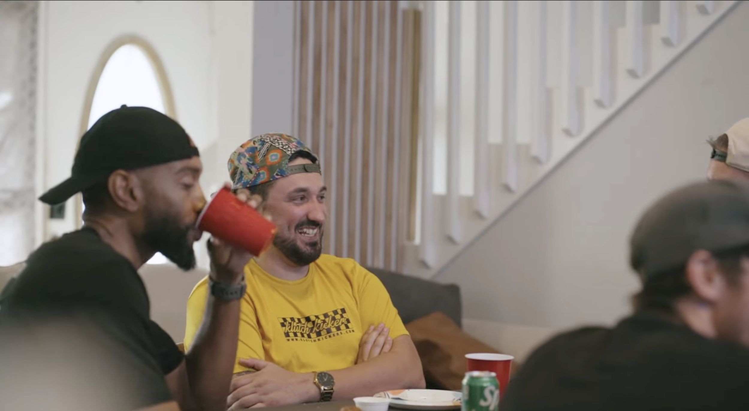 Group of friends sitting at a table, smiling and socializing, with drinks and snacks in a cozy indoor setting.