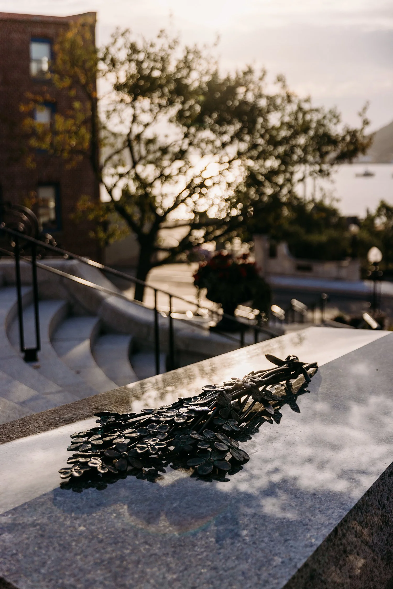 Close-up shot of Newfoundland National War Memorial, showing tomb of Uknown Soldier with metal flowers on top, with St. John's harbour visible in the background.