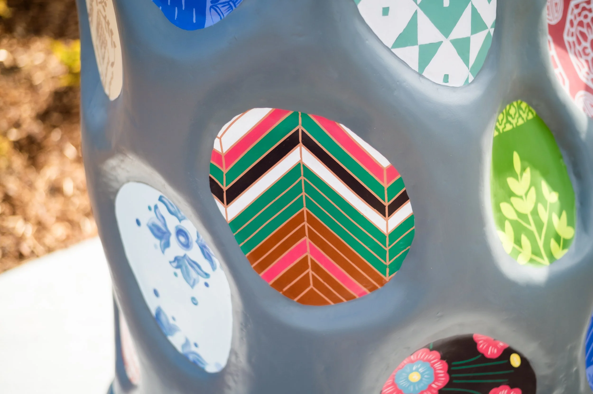 Various circular patterns featuring different designs of flowers and other shapes are featured on a mitten sculpture.