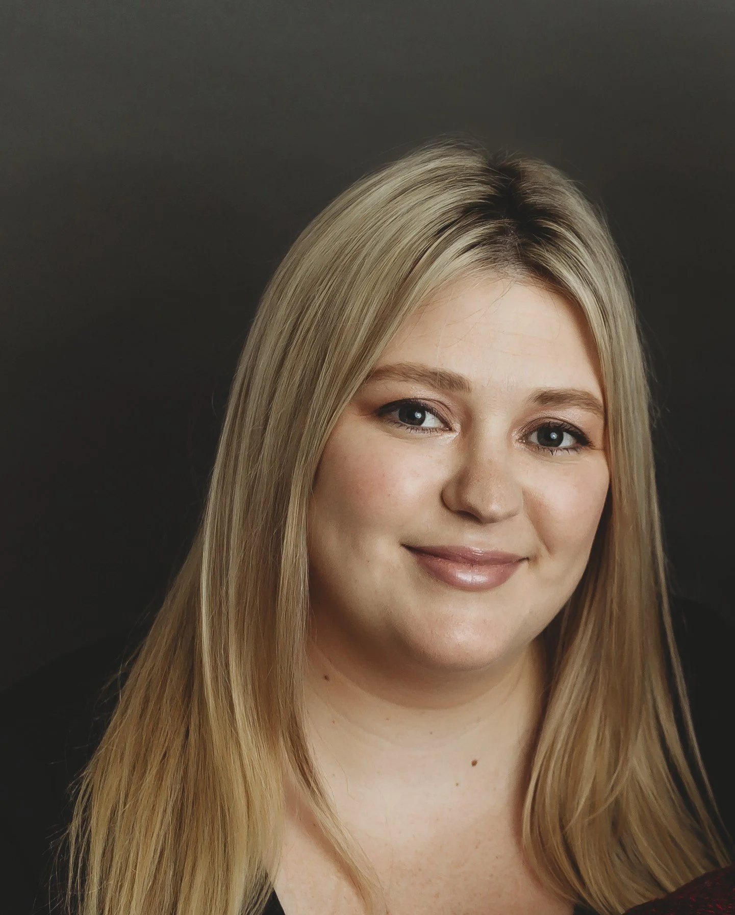 A woman with long blonde hair smiles at the camera.