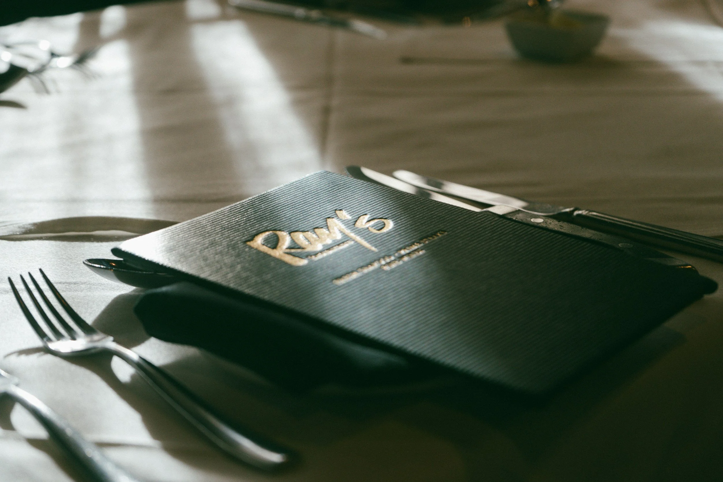 A textured restaurant menu that features gold metallic foil printing and a textured cover