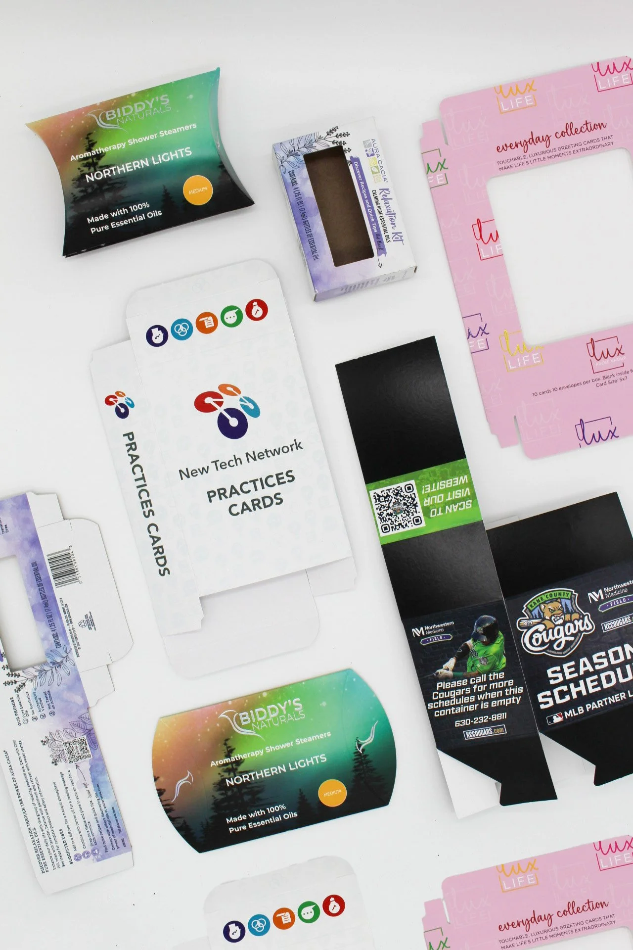 Various packaging designs including aromatherapy shower steamers, practice cards, and greeting cards displayed on a white surface.