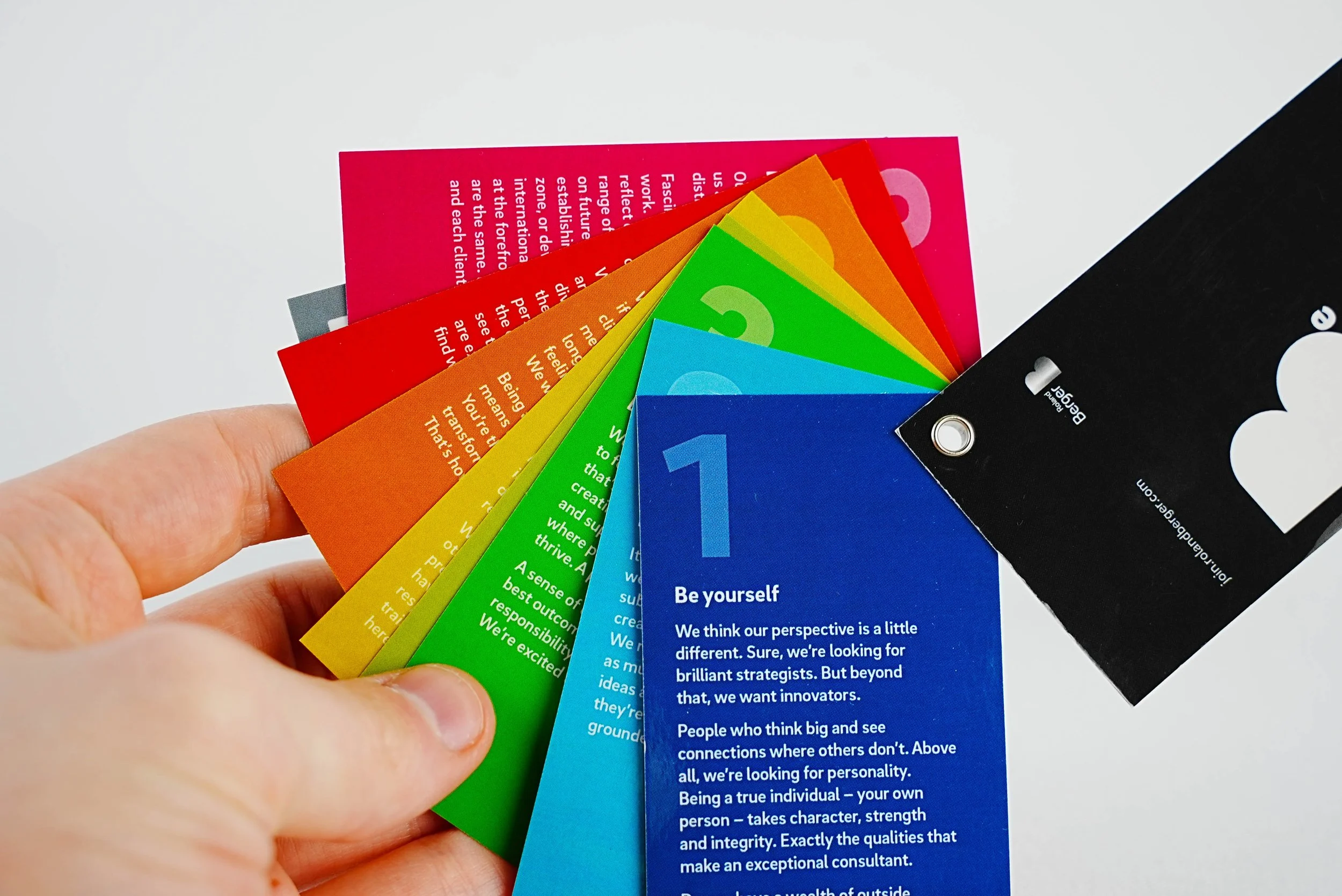Colorful laminated cards with motivational messages fanned out, held in a person's hand.