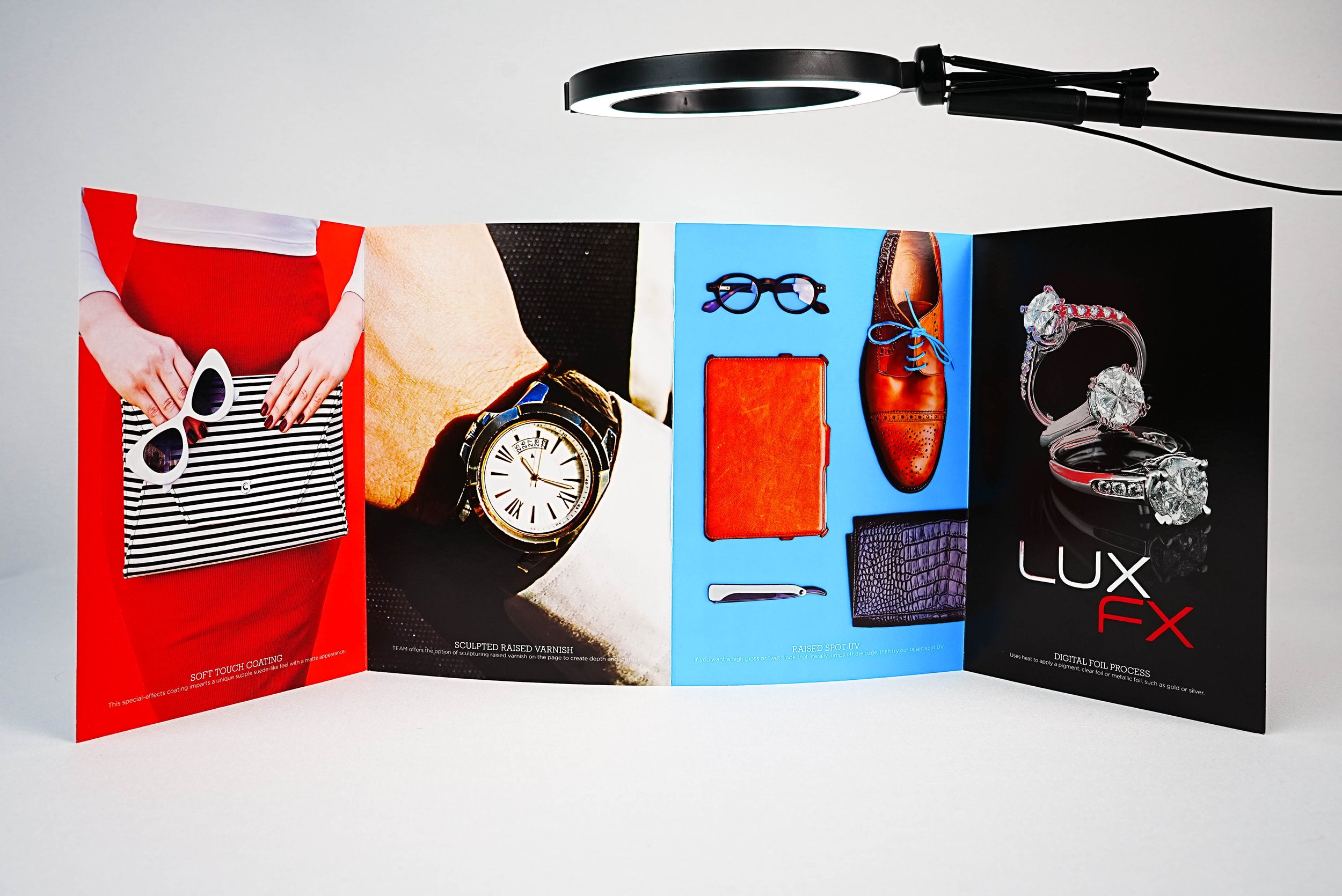 Four poster images under a ring light. First depicts a person holding sunglasses and a striped clutch against a red outfit. Second shows a luxury watch on a wrist. Third features elegant accessories like glasses, shoes, and wallet on a blue backgroun