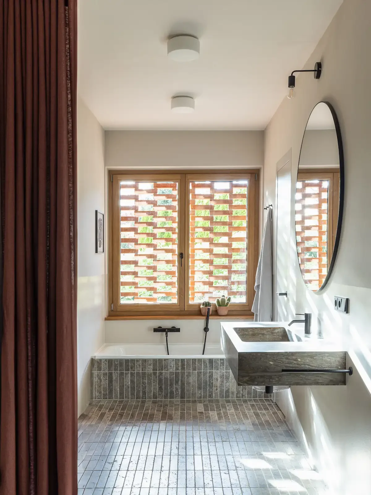 Badezimmer mit Natursteinwaschtisch und Lochziegel-Fenster als Sichtschutz