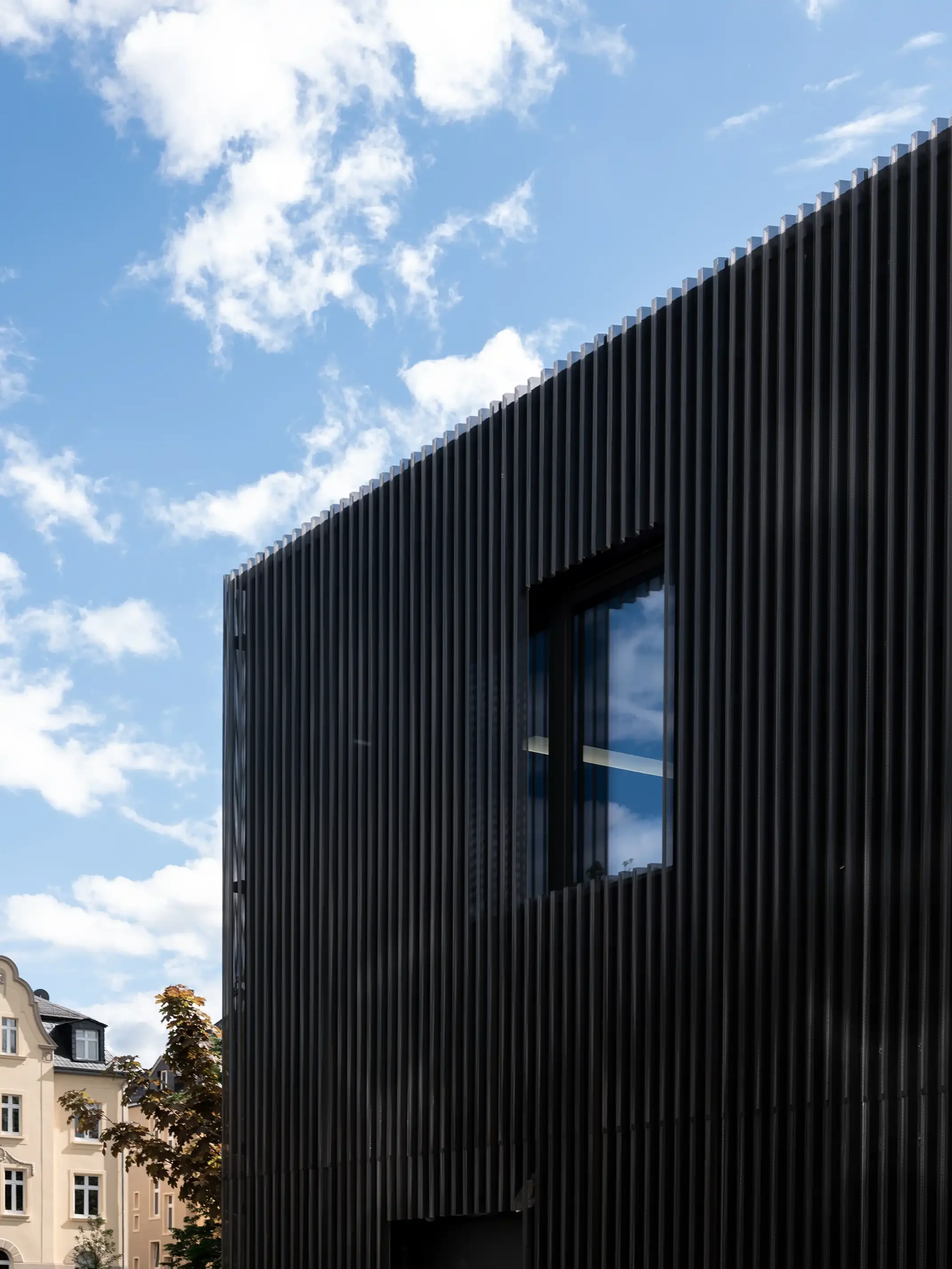 Fassadendetail: schwarze, perforierte Metallfassade