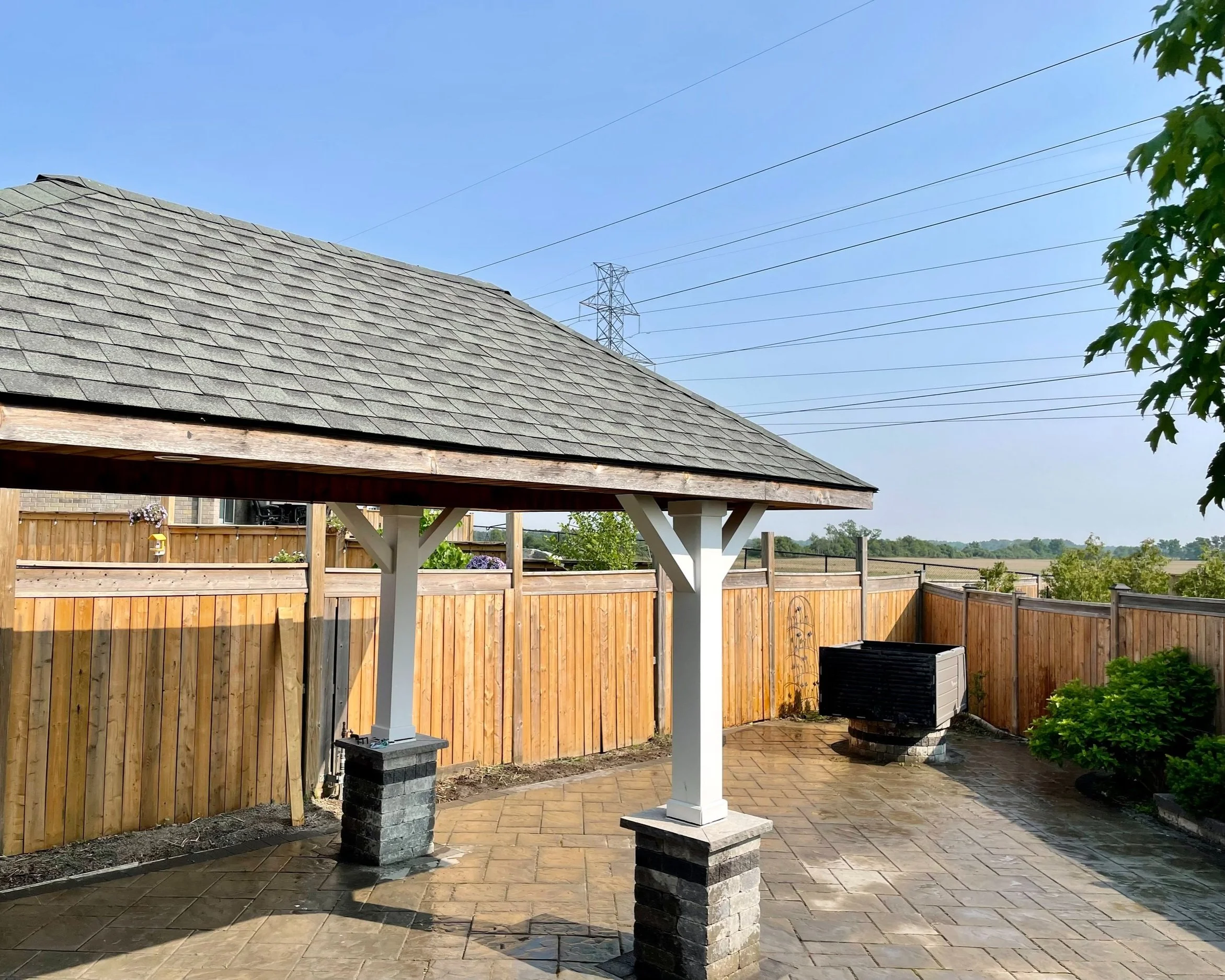 Calgary backyard patio with wooden pergola, stone columns, and wooden fence