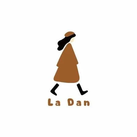 Dibujo simplificado de una mujer caminando, con el cabello y el sombrero en color marrón, el vestido marrón y las piernas en negro, con el texto 'La Dan' debajo.