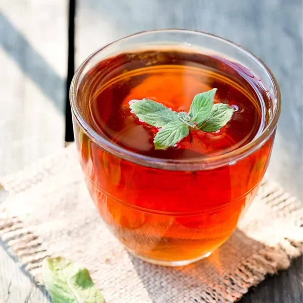 Finished Ruby Red tea served hot, garnished with mint – vivid amber color.
