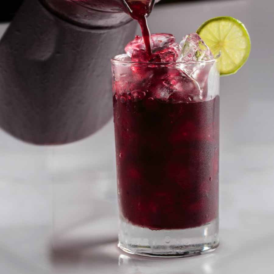 Iced grape drink with lemon and ice – tangy and refreshing in vibrant purple.
