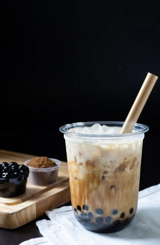 Layered brown sugar boba milk drink with syrup drips and chewy tapioca pearls