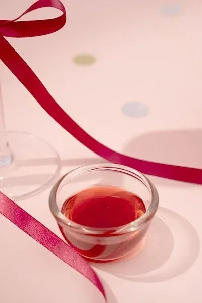 A small glass dish filled with vibrant red fruit syrup — perfect for fruit teas, slushes, and sparkling drinks