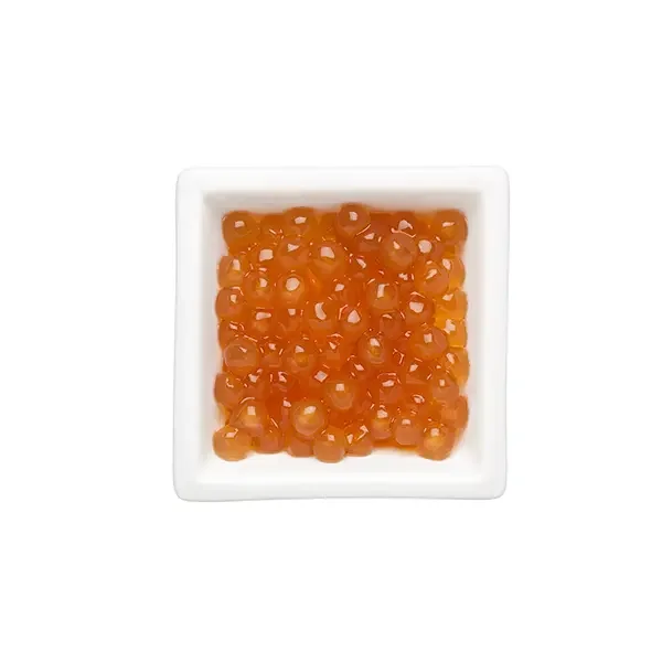 Golden tapioca pearls in a white dish, showcasing their vibrant amber color and glossy texture for milk tea and desserts.