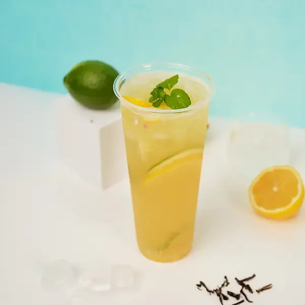 Refreshing iced lemon tea made with lemon syrup, garnished with fresh lemon slices and mint leaves in a clear cup.