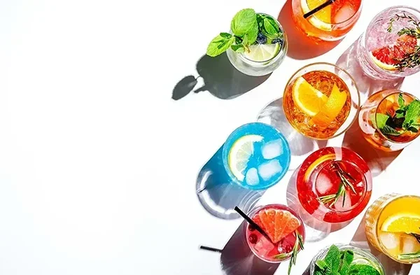 Assorted colorful drinks with citrus, herbs, and fruit garnishes – ideal for fruit syrup, jam, or creative beverage applications.