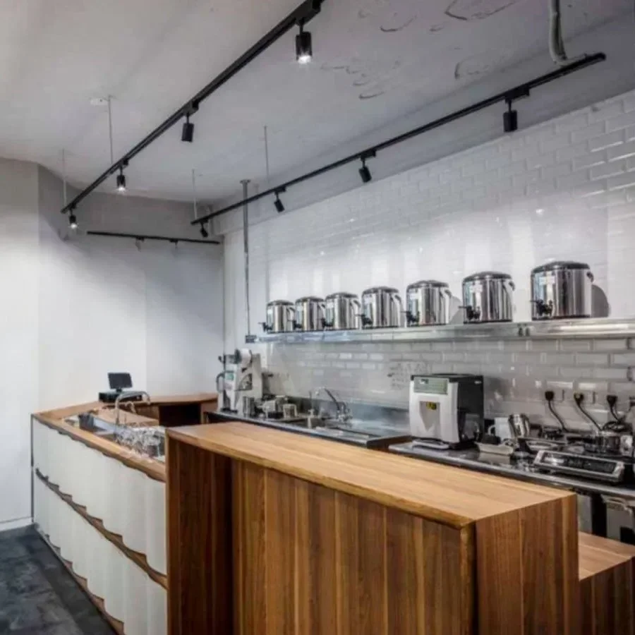 Modern industrial-style kitchen with white brick backsplash, wooden counter, and stainless steel appliances including multiple rice cookers or kettles.