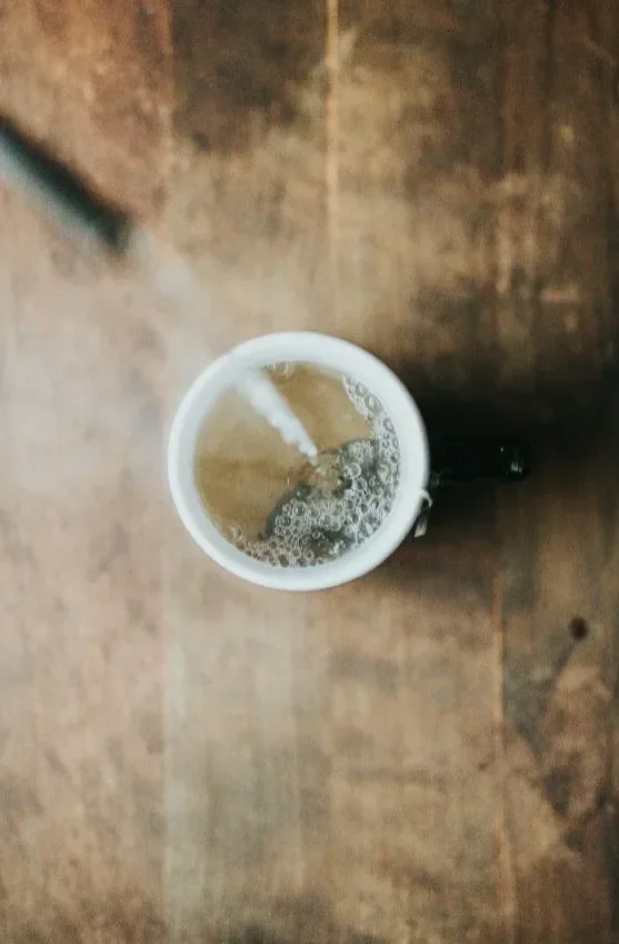 Hot tea pouring into a cup from top view, representing flavor consistency and professional tea base solutions