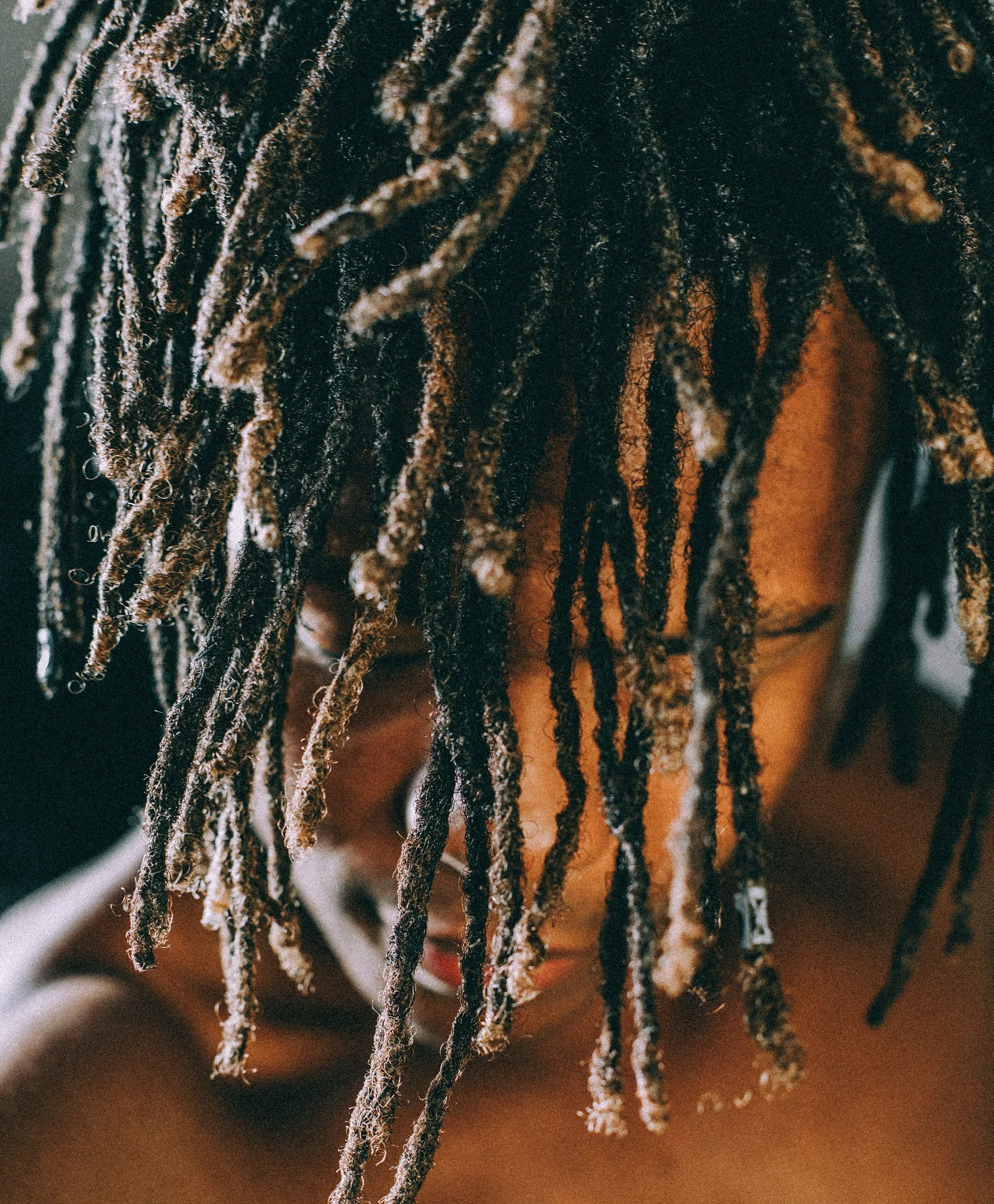 Close-up of dreadlocks with some covered in white dust or ash, on a person wearing a yellow shirt.