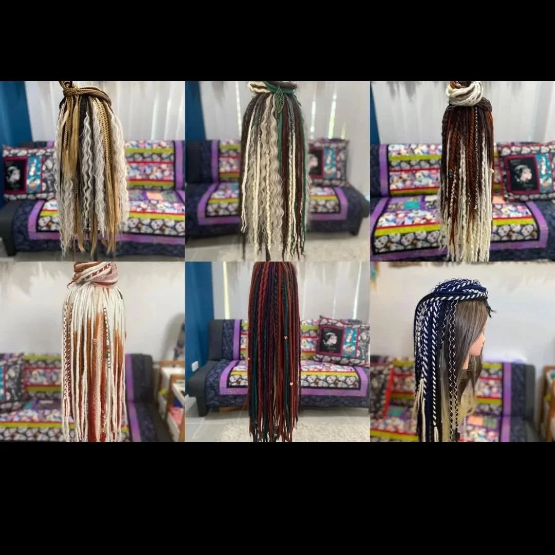 Collection of colorful synthetic dreadlocks hair extensions displayed over a black and colorful fabric sofa with quilted patterns and cushions.