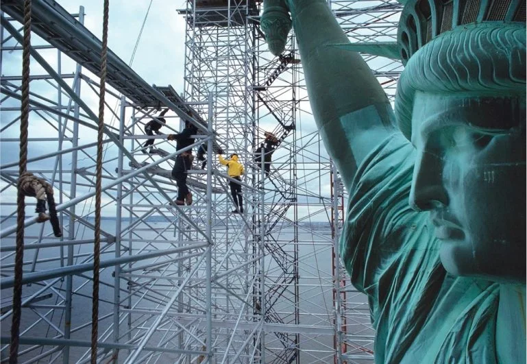 Construction workers on scaffolding near the Statue of Liberty's face in New York City.