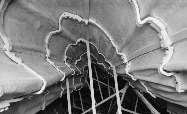 Looking up inside a large, spiral-shaped industrial or construction tunnel with scaffolding and support beams visible.