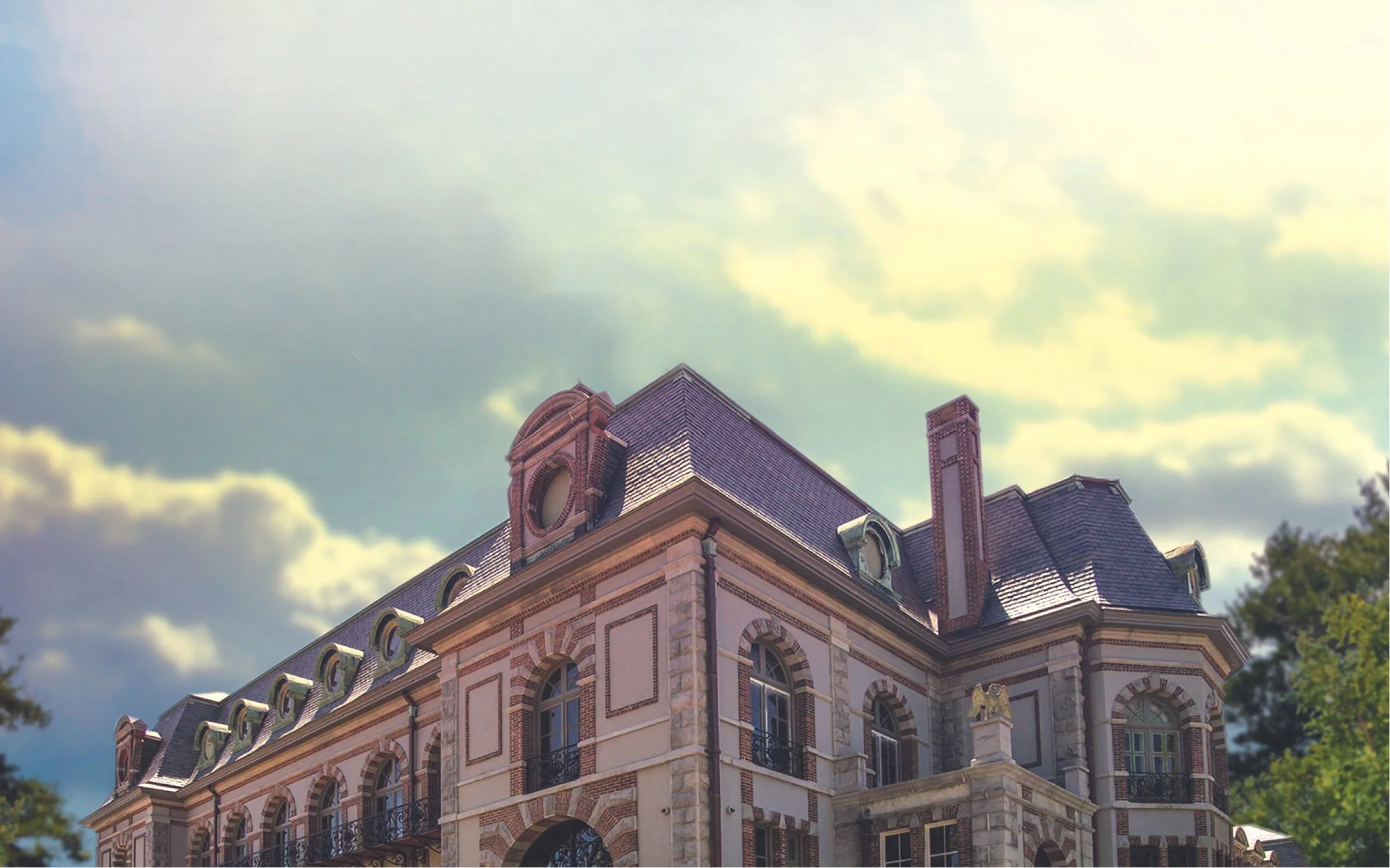 Historic European-style building with ornate details and a slate roof, under a partly cloudy sky.