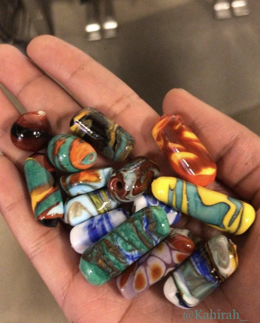 A hand holding several colorful glass marbles with various swirling patterns and colors.