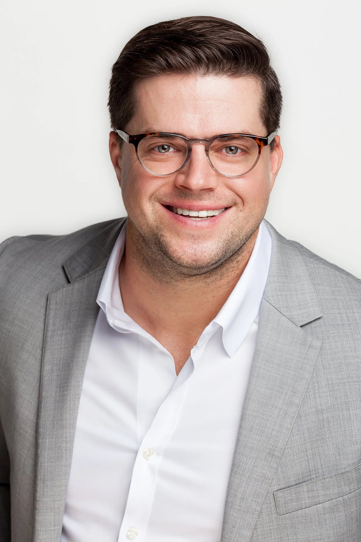 Corporate Young man in a blazer smiling and looking straight at camera.