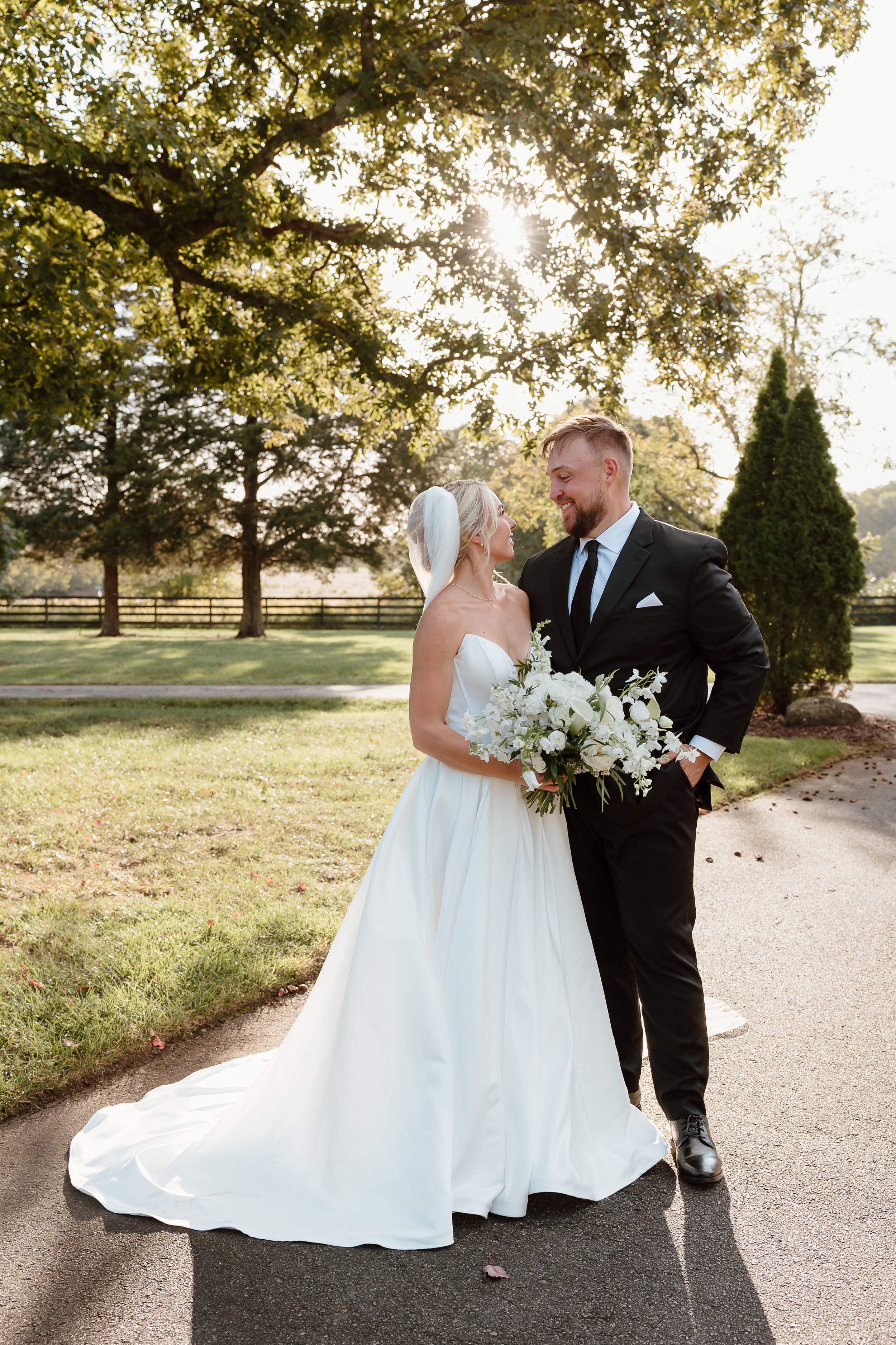 A bride and groom sharing a tender moment under a wedding veil outdoors.