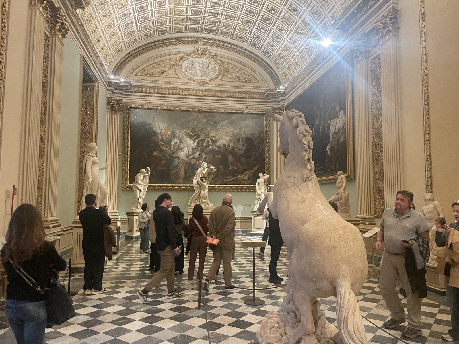 Classical museum room with sculptures and a large painting.