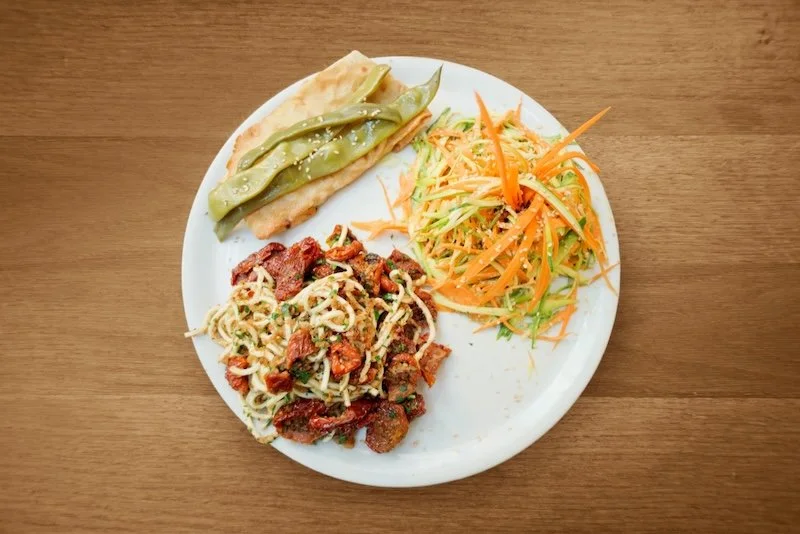 Plate with artisinal, fresh food, including pasta and vegetables.