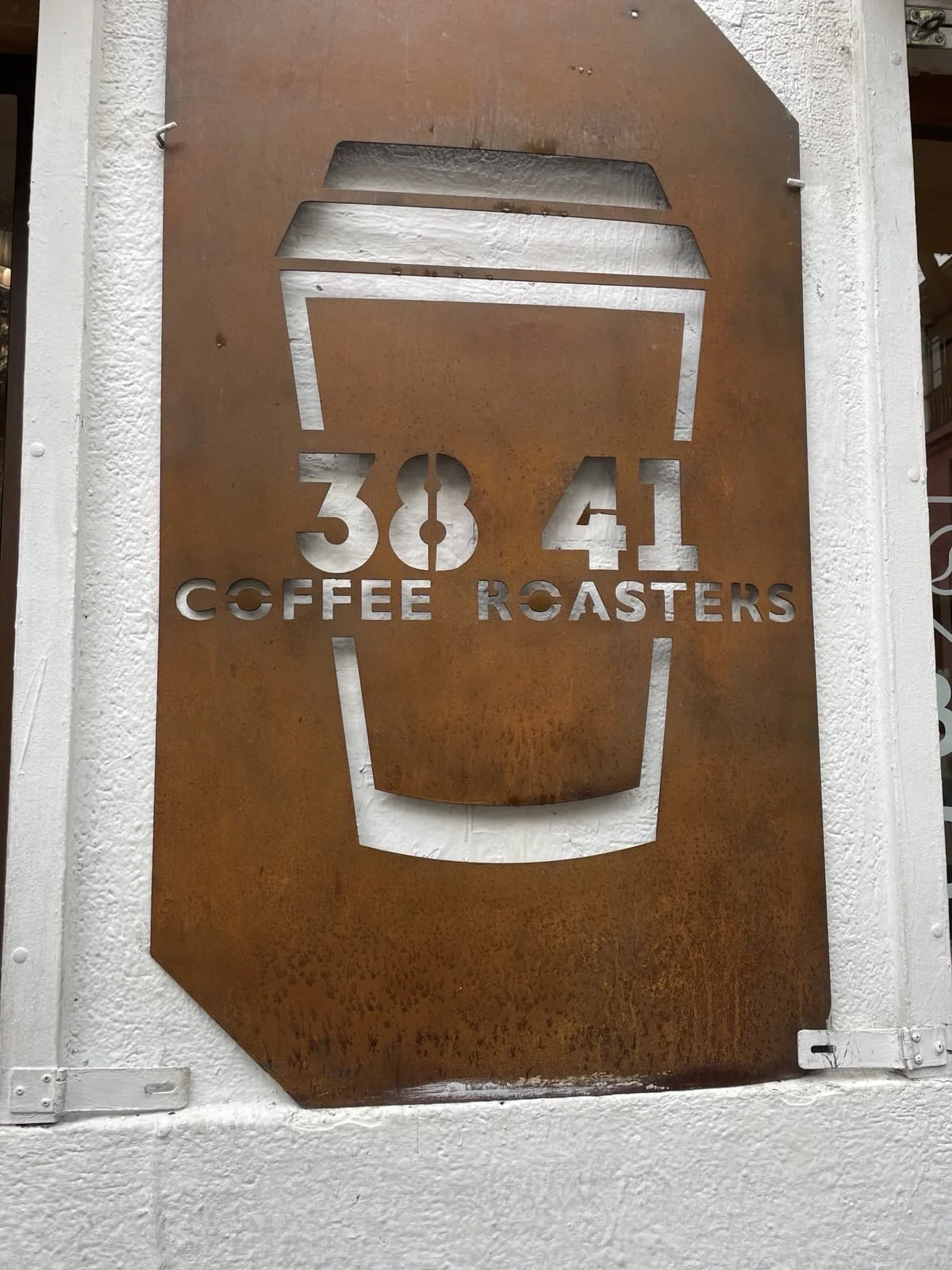 Rust coloured outdoor sign for coffee shop with coffee cup outline.