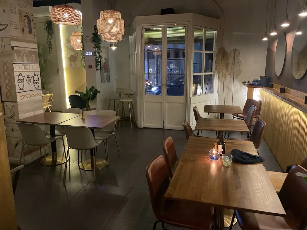 Restaurant interior with tables and chairs, and some Egyptian illustrations on the walls.