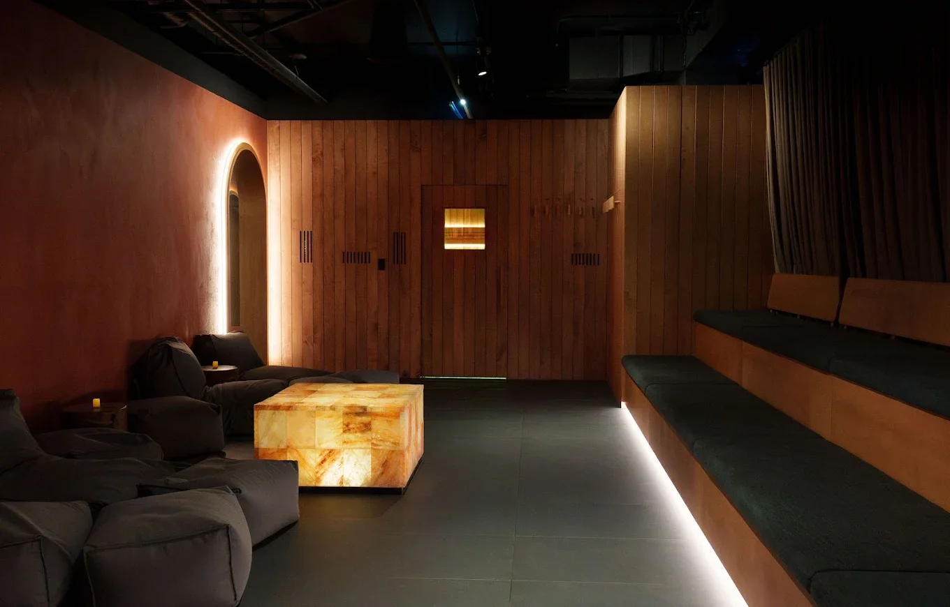 Dimly lit sauna interior with cushions and a bright marble-looking table.