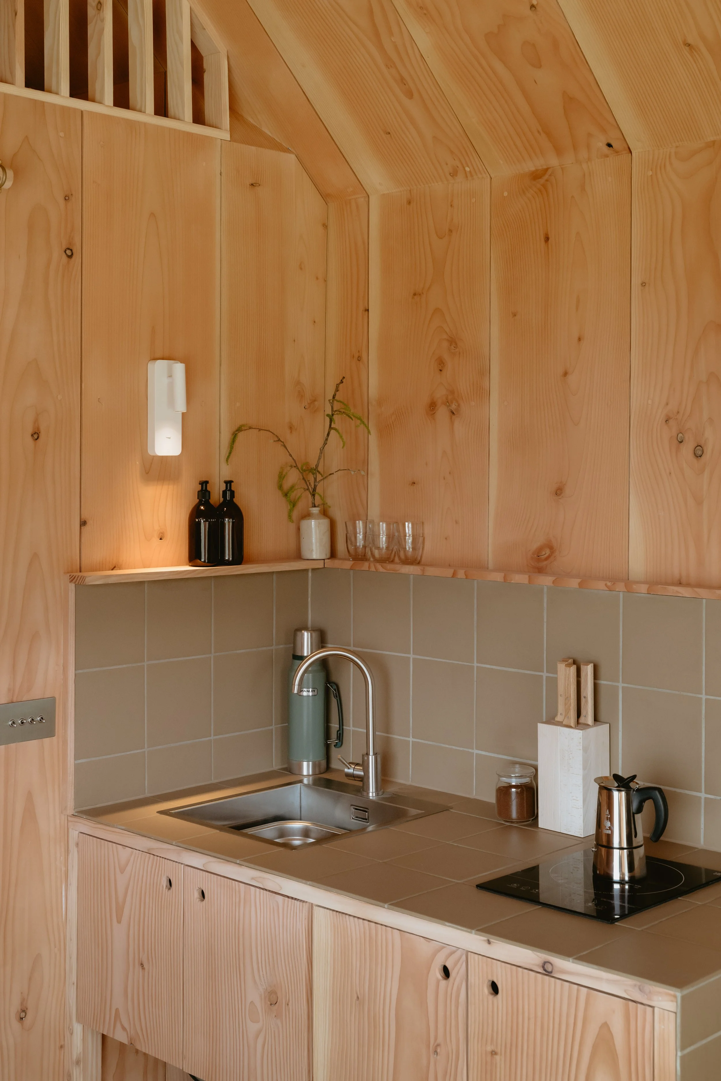 A little but perfect kitchen with sink and induction hob for the sunny days when the stove may be too warm. Douglas fir wood cladding on the walls as well as lovely putty coloured earth tiles. 