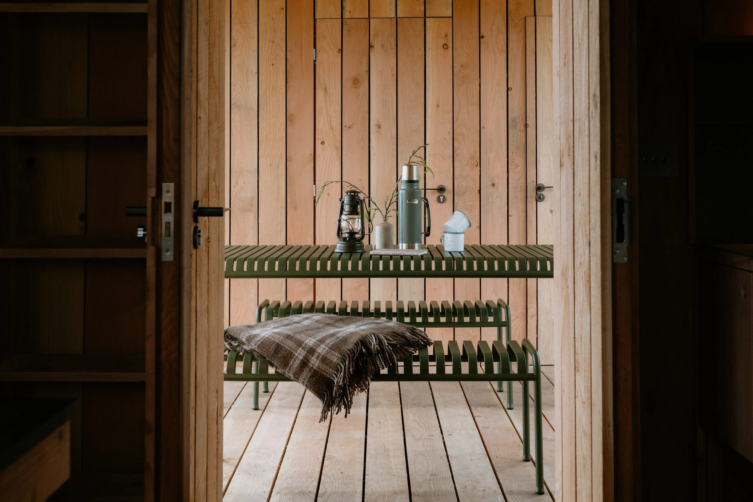 A green Hay table and benches outside, with stanley flask and a homespun wool blanket. 