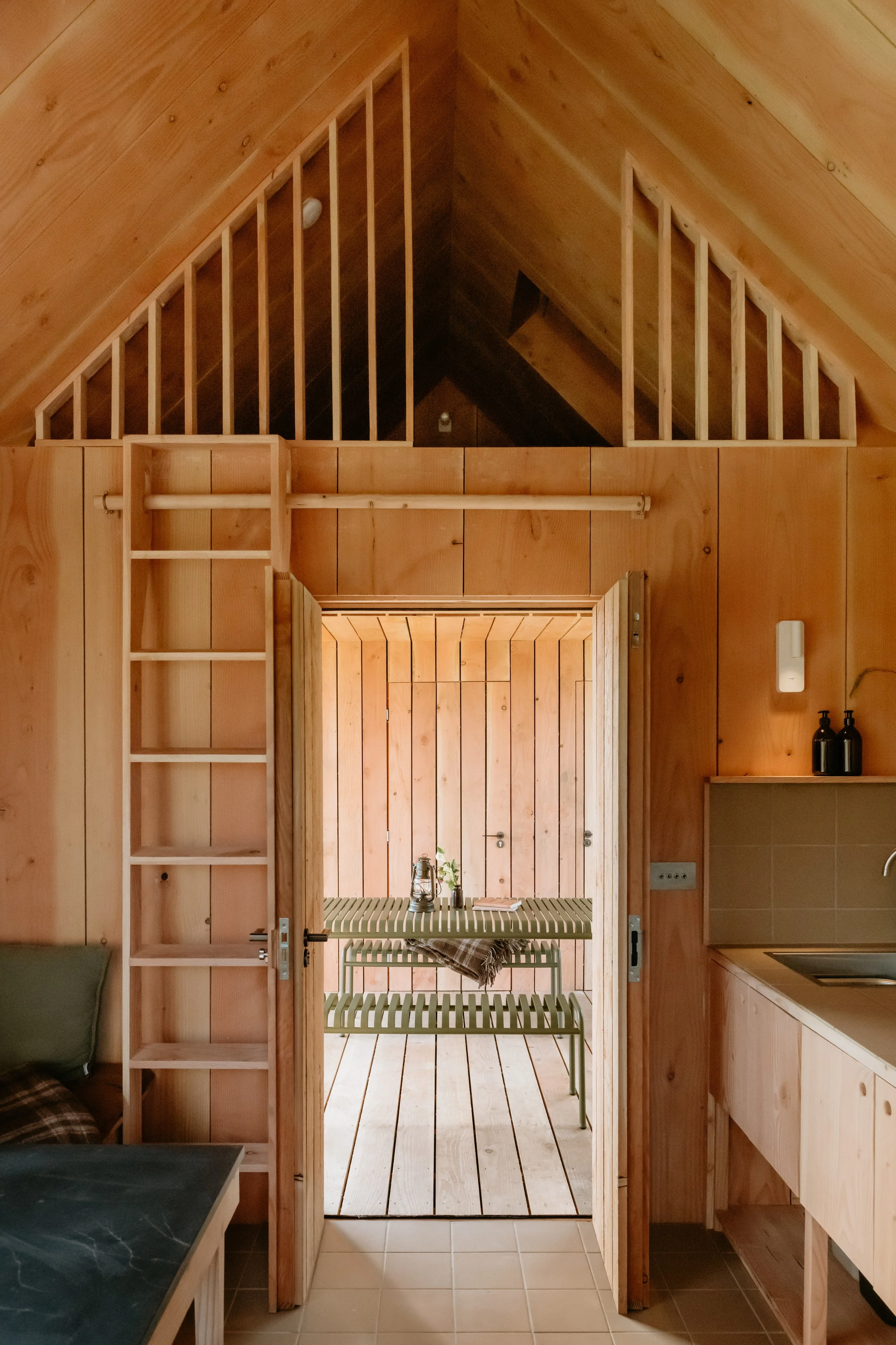 The view out the door to the covered outside space, which closes over to become another room. The mezzanine bed above, with the ladder tucked back against the wall. 