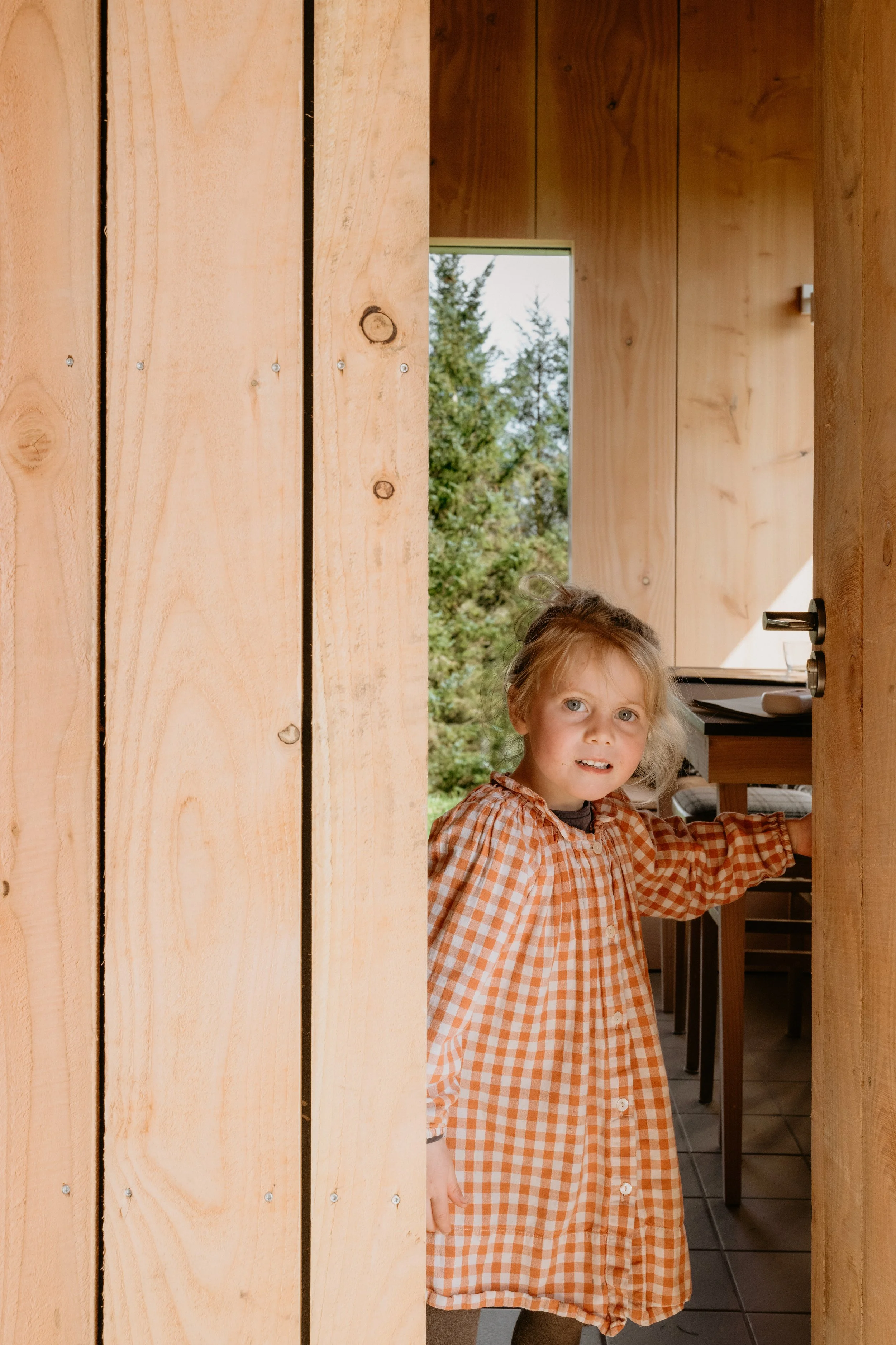 A little girl in a gingham dress welcomes you into the hut.