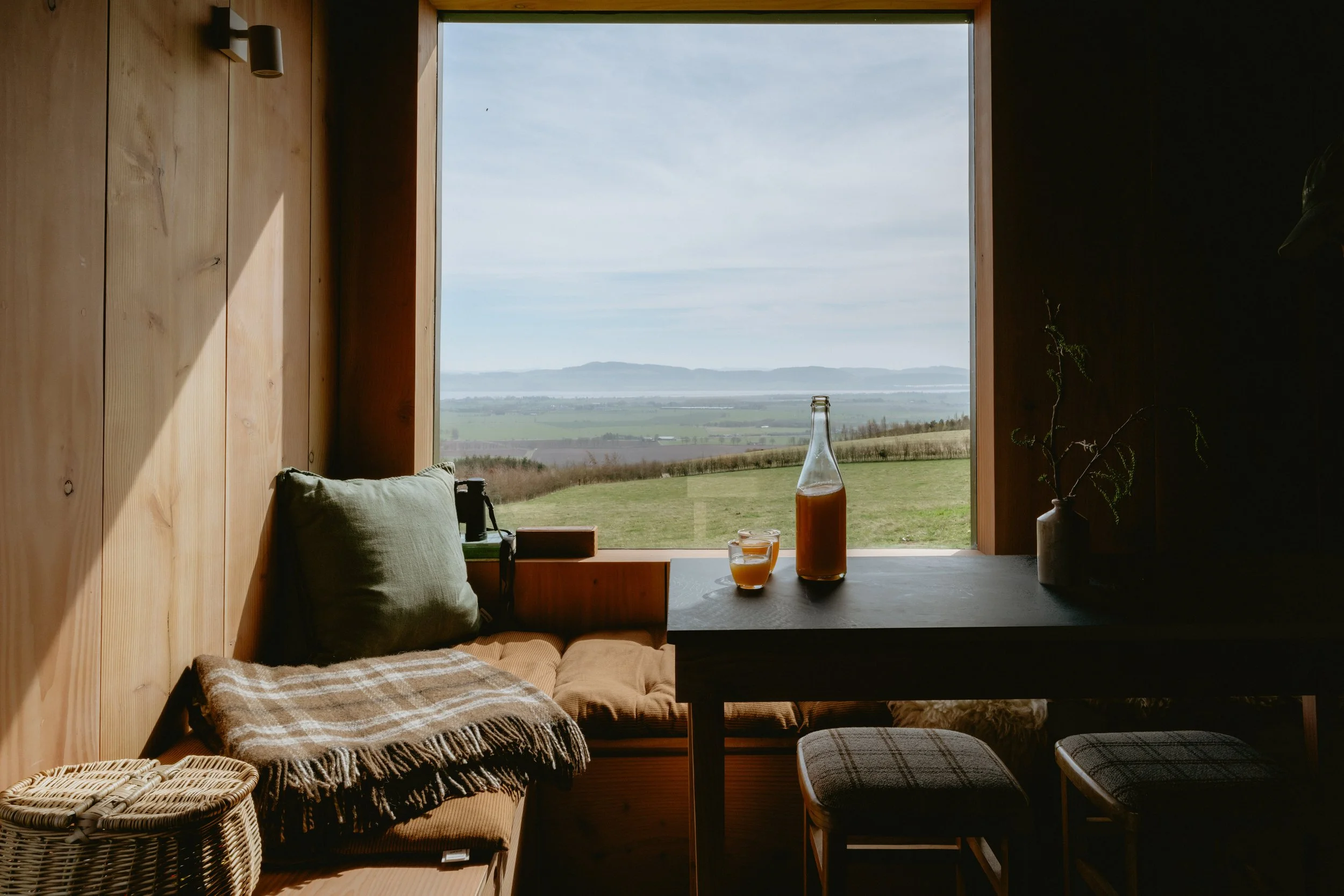 The view from the cabin across to the Lomonds in Fife. Cosy blankets, comfy window seats and homemade apple juice on the table.