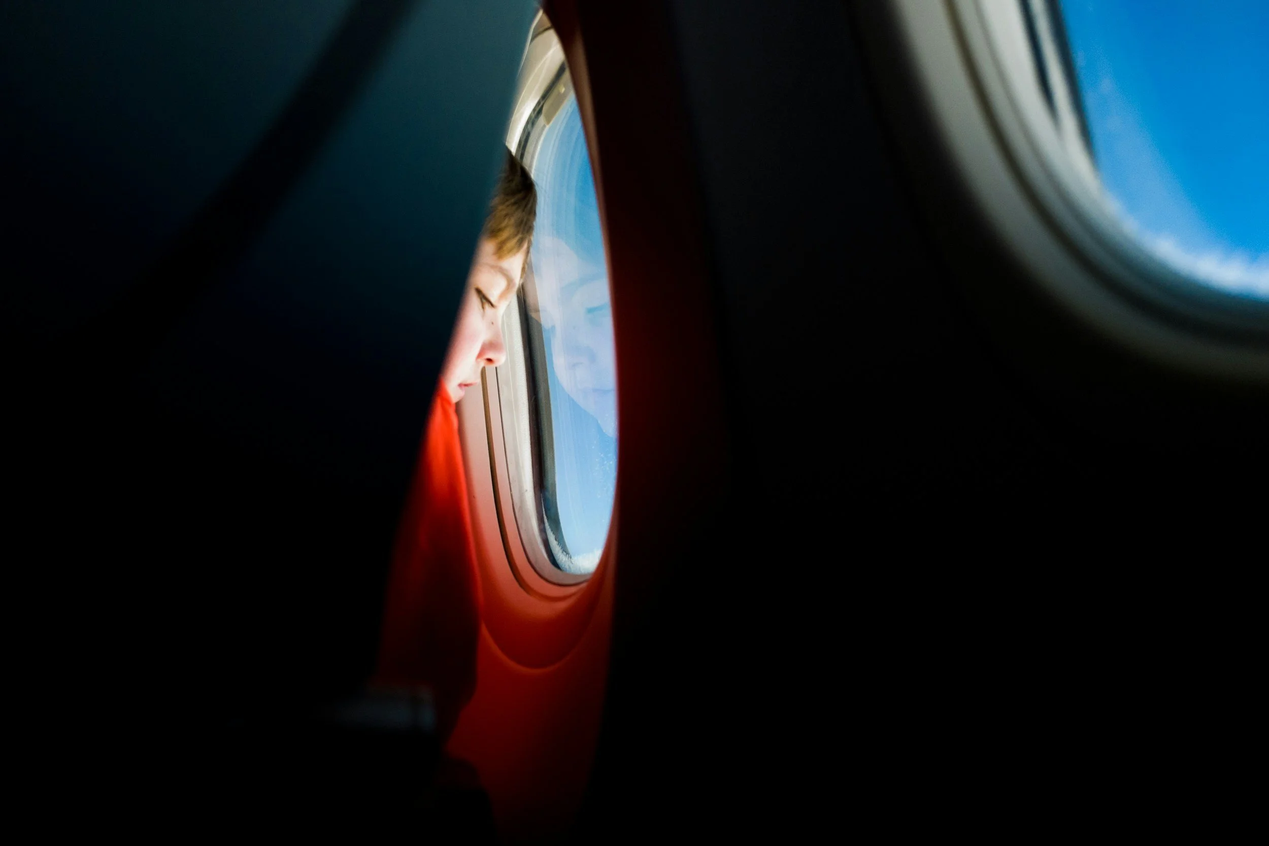 A passenger looking out the window of an airplane, viewed through the oval aircraft window.